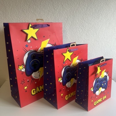 Três sacos de papel vermelhos com comando de videojogos e texto 'GAME ON'