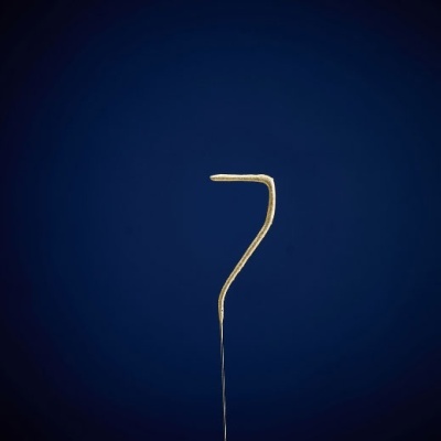 Agulha metálica fina com parte superior curvada sobre fundo azul escuro