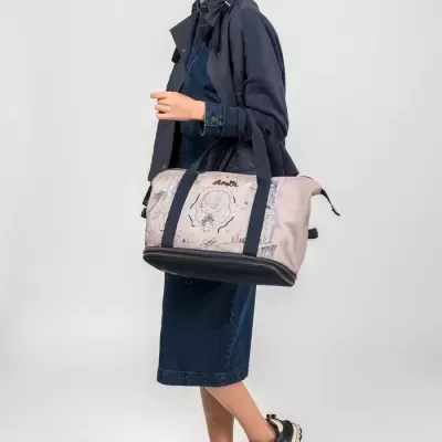 Mulher com mala tipo saco bege, vestida em azul escuro e ténis pretos com dourado