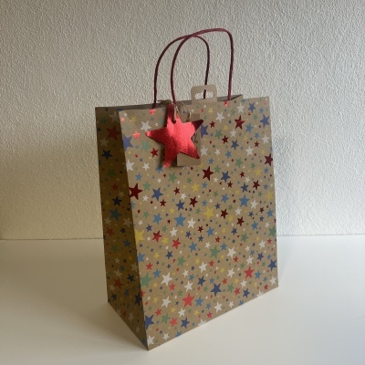 Saco de papel castanho com estrelas coloridas e pega de corda vermelha