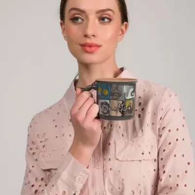 Mulher a segurar uma caneca preta decorativa com padrão colorido