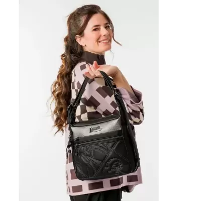 Mulher a segurar bolsa preta com textura e padrão geométrico em camisa castanha e bege