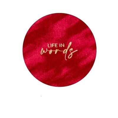 Círculo vermelho aveludado com texto 'LIFE IN words' em dourado