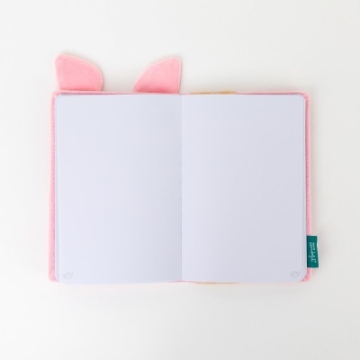Caderno rosa com orelhas de gato aberto mostrando páginas em branco