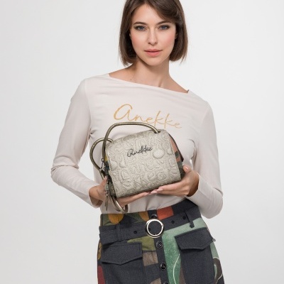 Mulher com blusa bege e saia colorida a segurar mala bege Anekke