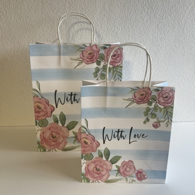 Duas sacolas de papel com riscas azul claro e flores rosas, texto 'With Love' e alças de corda branca