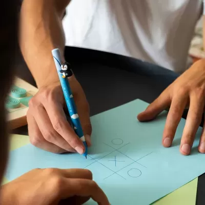 Caneta azul com pinguim e jogo da velha no papel azul