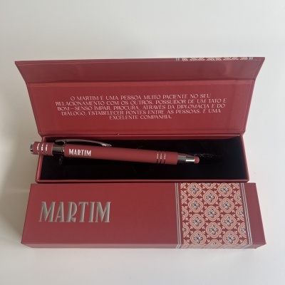 Caneta vermelha Martim numa caixa vermelha decorada, texto em português na parte interior da tampa.