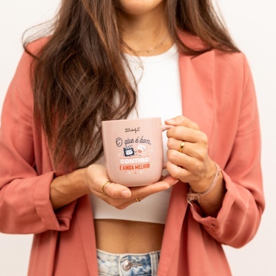 Caneca rosa com mensagem segurada por mulher com casaco cor de rosa e top branco