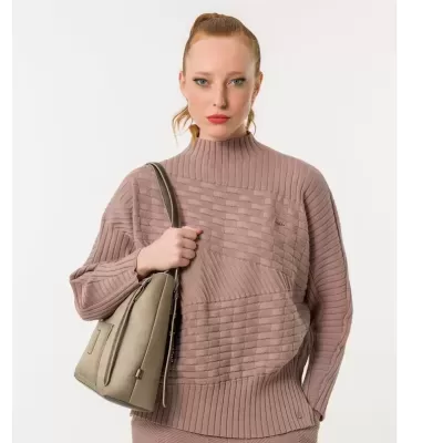 Mulher com camisola rosa de malha e mala bege de couro