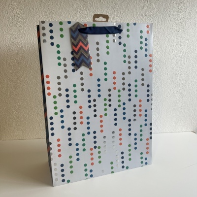 Saco de papel para presente com bolinhas coloridas, alças azuis e etiqueta zig-zag