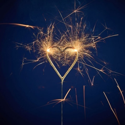 Vela fogo-de-artifício em forma de coração a arder com faíscas douradas