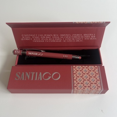 Caixa e caneta vermelhas com padrão decorativo e texto em português