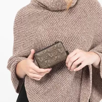 Mulher a segurar carteira em relevo castanha com poncho de malha castanha