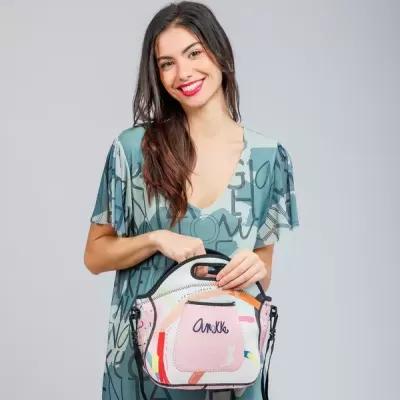 Mulher com vestido azul e mala pequena colorida na mão