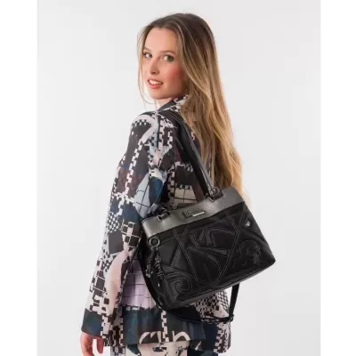 Mulher com bolsa preta Anekke e blazer padrão geométrico