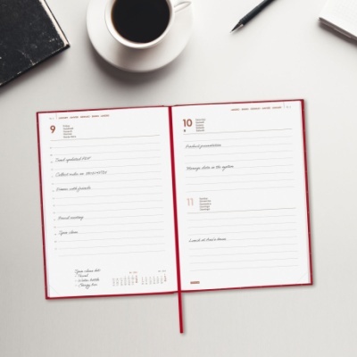 Agenda aberta nas datas 9 e 10 com caneta, caderno, e chávena de café num fundo branco