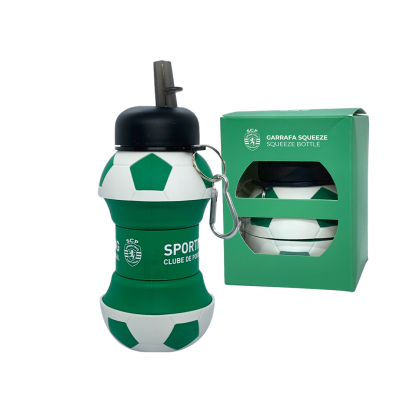 Garrafa squeeze verde e branca com design de bola de futebol e tampa preta com mosquetão, ao lado da embalagem verde.