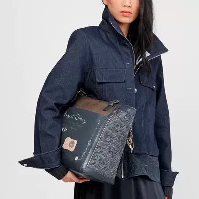 Mulher com casaco azul escuro e mala azul texturizada