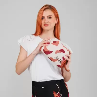 Mulher ruiva com blusa branca e saia preta segurando bolsa pequena com corações vermelhos e rosa.