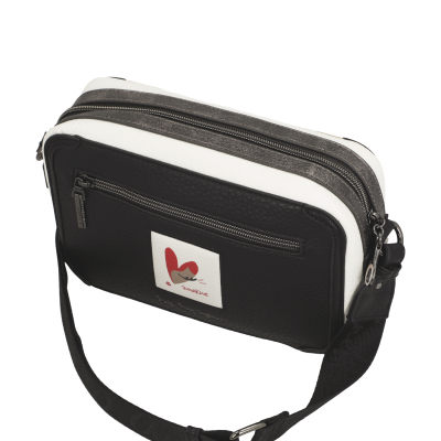 Mala tiracolo preta e branca com bolso frontal e etiqueta decorativa