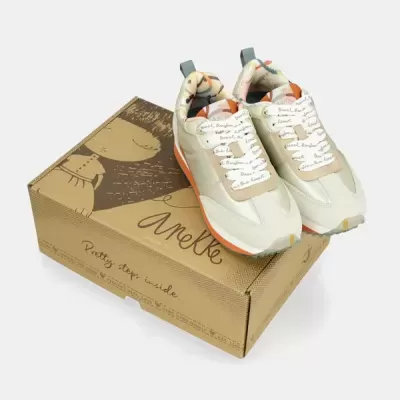 Sapatilhas bege e branco com detalhes cor de laranja sobre caixa castanha Anekke