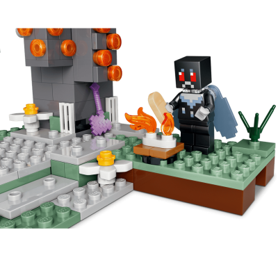Figura LEGO de personagem com máscara preta e capa azul numa base verde e cinza com construção cinzenta e detalhes laranja