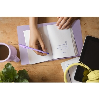 Mesa com caderno aberto, caneta, chá, headphones e tablet