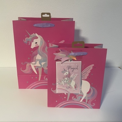 Duas sacolas rosa com unicórnios coloridos e cartão com texto 'WISHING YOU A Magical Day'