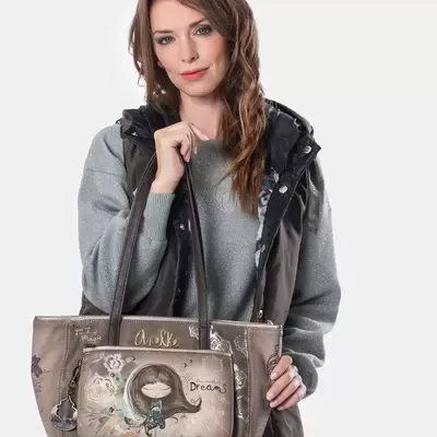 Mulher segurando mala taupe ilustrada com texto Dreams e Anekke