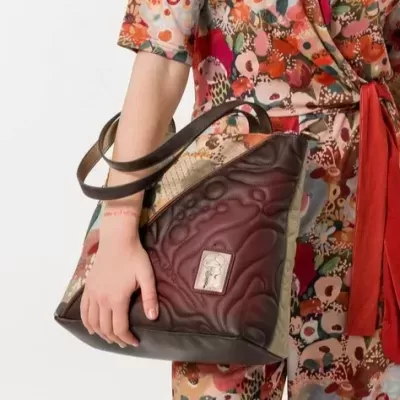 Mochila castanha texturizada com padrão animal print nas laterais e etiqueta com desenho de rosto