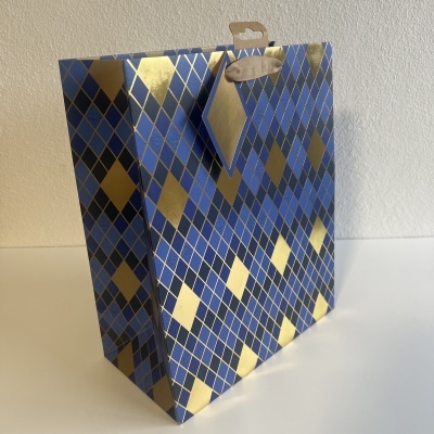 Saco de presente azul com padrão de losangos dourados e etiqueta pendurada