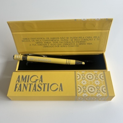 Conjunto de caneta e caixa amarelos com texto 'AMIGA FANTÁSTICA' em dourado