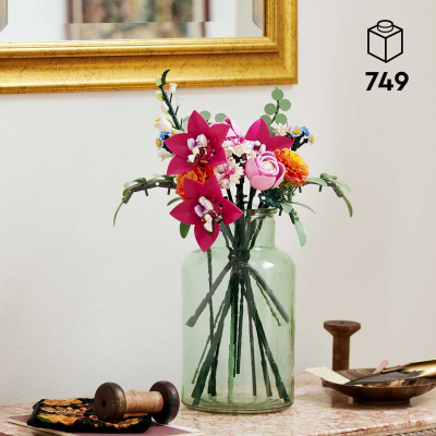 Vaso verde com flores artificiais coloridas numa mesa com objetos decorativos