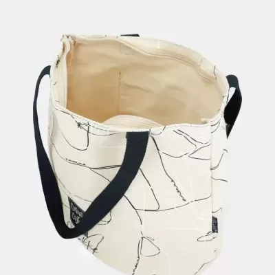 Bolsa de tecido bege com alças pretas e padrões abstratos