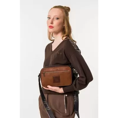 Mulher com camisola castanha e mala de couro castanha com alça preta e detalhes dourados