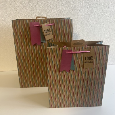 Dois sacos de papel reciclável com padrão ondulado colorido e etiquetas 100% RECICLÁVEL