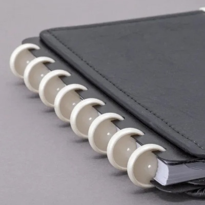 Caderno preto com argolas brancas sobre superfície cinza