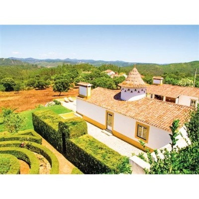 Casa tradicional branca com telhado de telhas vermelhas e jardim com sebes verdes aparadas