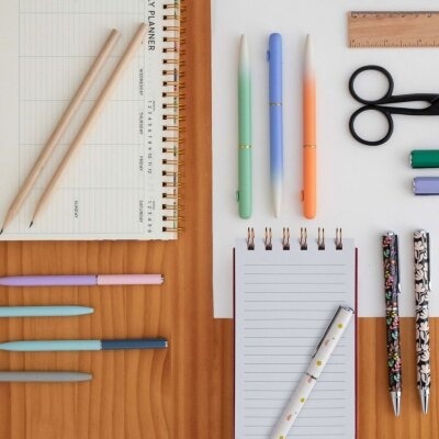 Mesa de madeira com cadernos, lápis, canetas, régua, tesoura e borrachas organizados