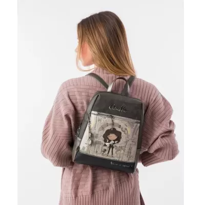 Mochila preta com ilustração e textos Anekke, usada por mulher de casaco rosa.