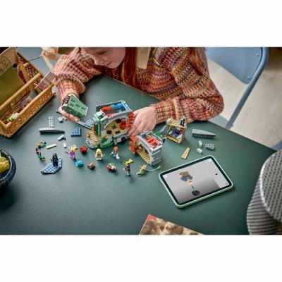 Criança a jogar com LEGO e tablet numa mesa verde