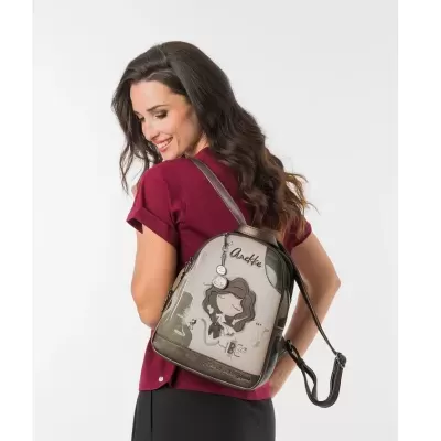 Mochila pequena Anekke castanha e bege com personagem, usada por mulher com camisa bordô e saia preta
