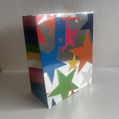 Saco de presente com estrelas coloridas em papel brilhante