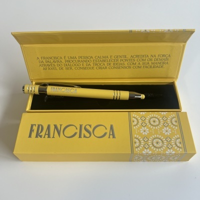 Conjunto de caneta amarela com caixa amarela decorada com texto e padrões brancos