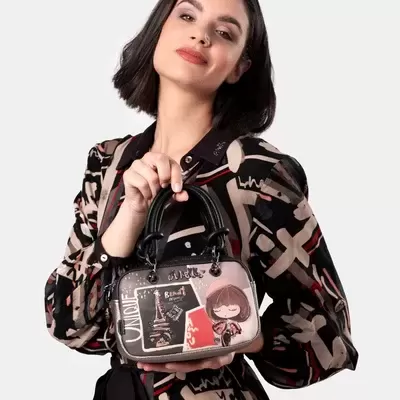 Mulher com vestido geométrico segura mala preta decorada com desenhos e texto