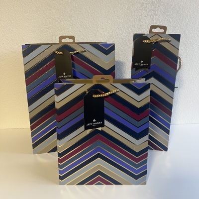 Sacolas de presente com padrão em zigzag colorido e etiquetas pretas com texto JEFF BANKS
