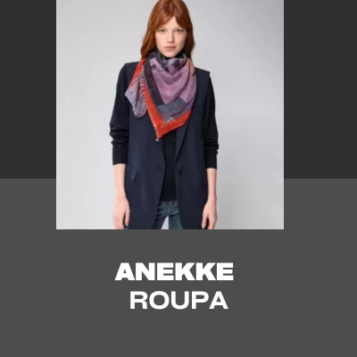 Mulher com lenço estampado roxo e vermelho, casaco preto e jeans azuis em fundo branco.