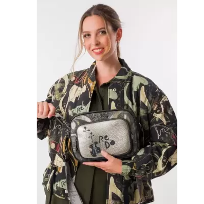 Mala de ombro prateada com desenhos e texto preto em mulher com casaco estampado