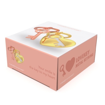 Caixa rosa para porta-chaves metálico com chave e coração dourado e texto em inglês.